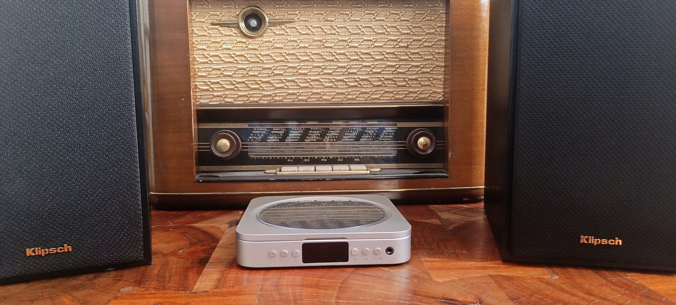 Fosi Audio Merak posé avec deux enceintes Klipsch R-41M et une TSF des années 50 en fond — contraste rétro-futuriste