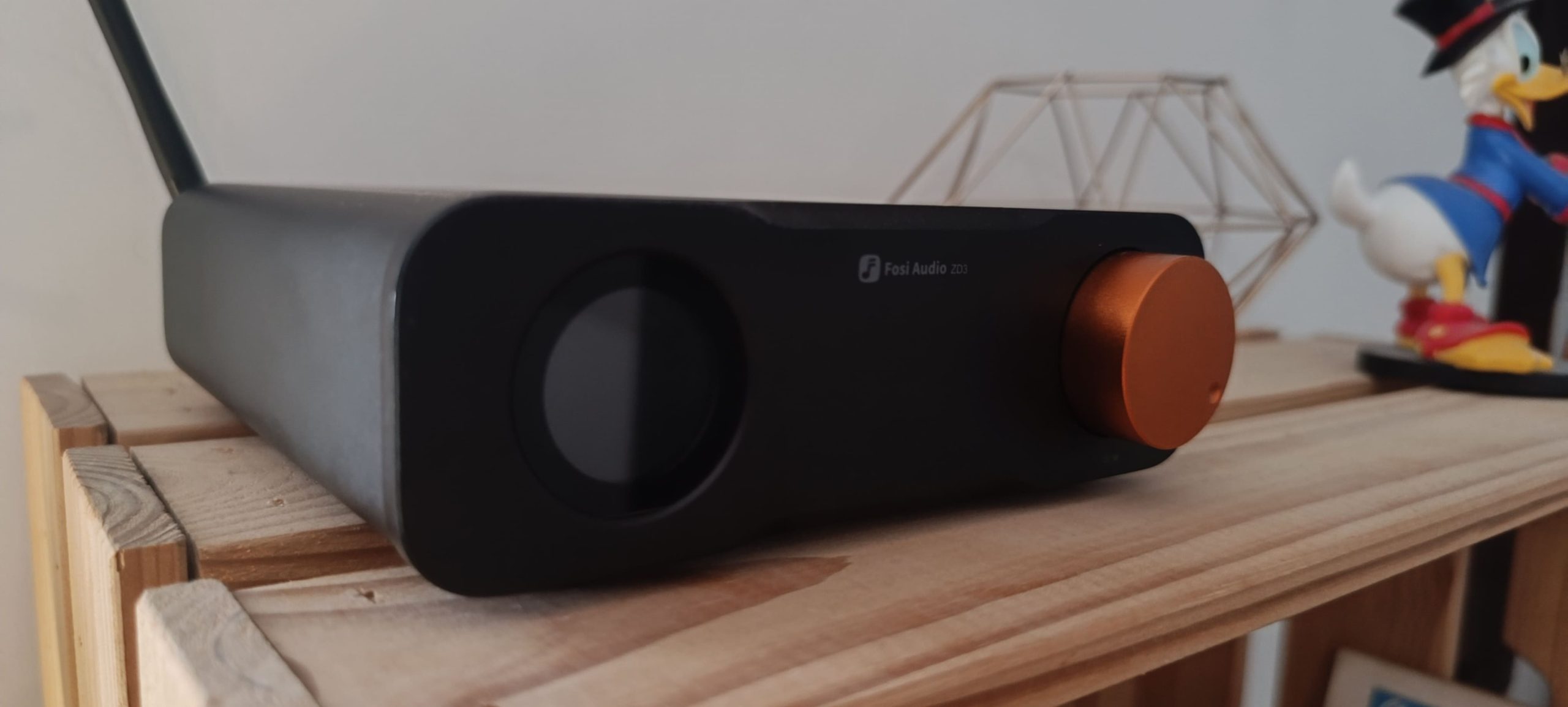 Fosi Audio ZD3 vue de face et de côté — écran OLED circulaire, bouton orange, châssis aluminium noir