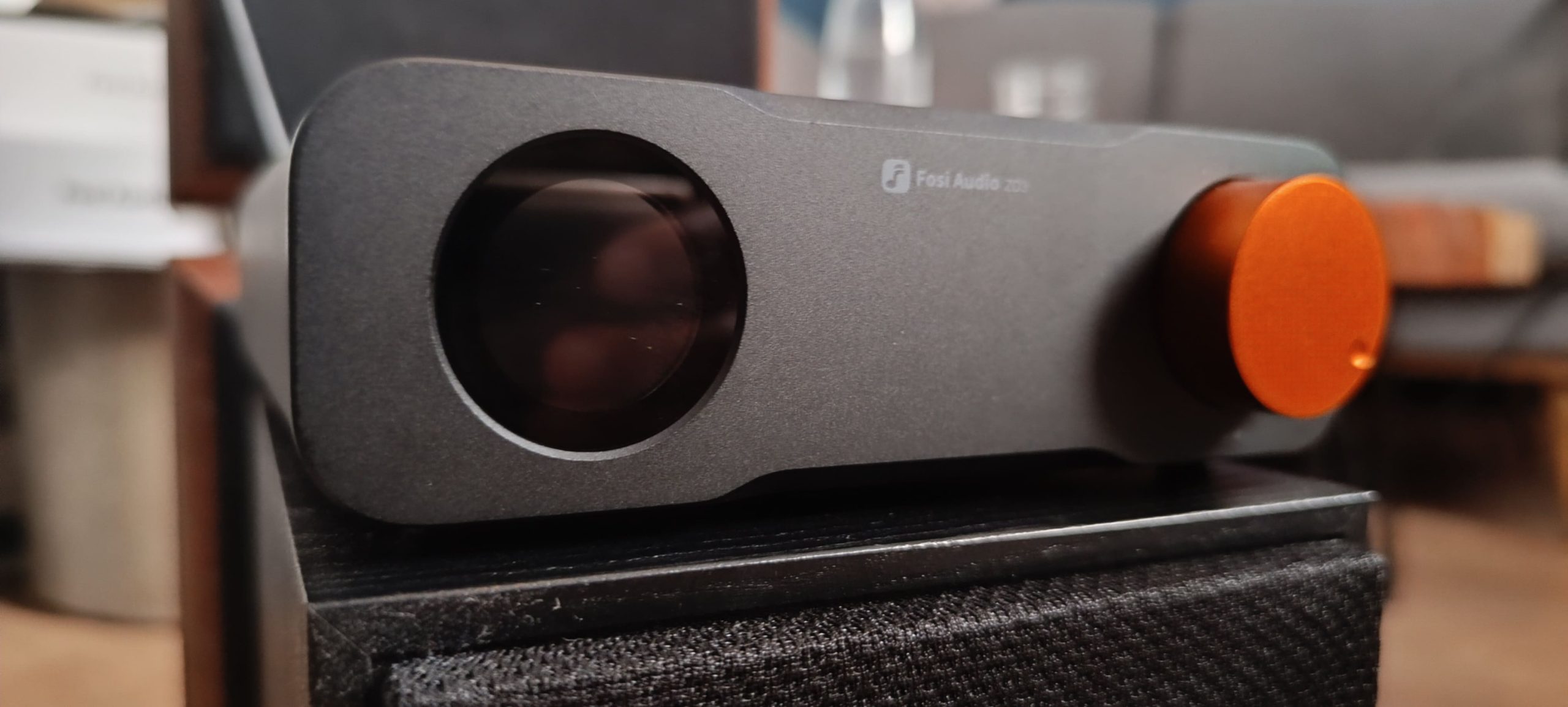 Fosi Audio ZD3 posé sur une enceinte — format desktop ultra-compact comparé à une enceinte bibliothèque